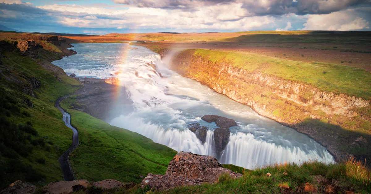 Gullfoss waterfall on Iceland’s Golden Circle with a bright rainbow rising from the mist.